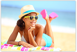 jeune femme allongée sur le ventre à la plage portant des lunettes de soleil 