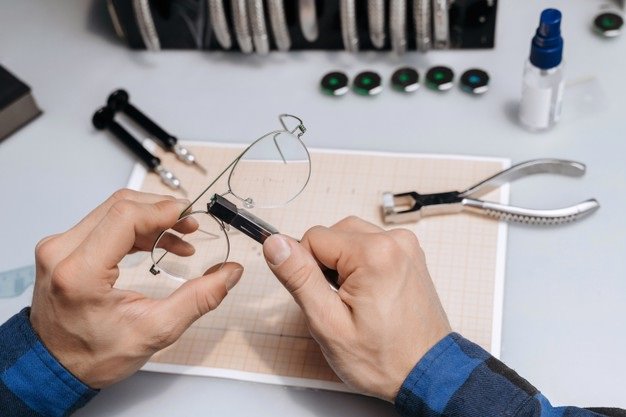 photo en gros plan des mains d'un opticien qui répare des lunettes